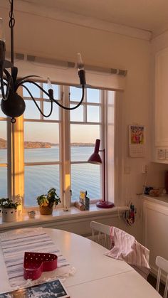 a kitchen with a table and chairs next to a large window looking out onto the water