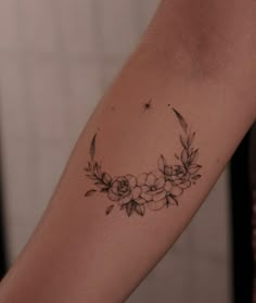 a woman's arm with flowers and a crescent tattoo on the left inner arm