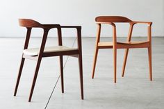 three wooden chairs sitting next to each other on top of a cement floor in front of a white wall