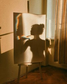 the shadow of a woman's head is shown on an easel