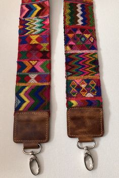 the straps are made out of leather and have colorful fabric on them, with metal hooks