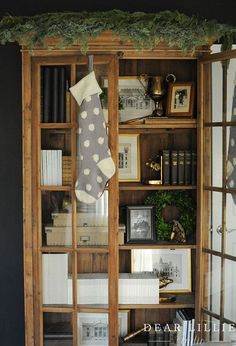 a wooden bookcase filled with books next to a christmas stocking hanging on the wall