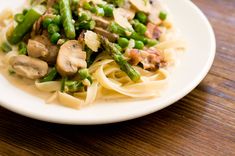 pasta with asparagus and mushrooms on a white plate