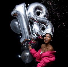 a woman is holding up some silver balloons