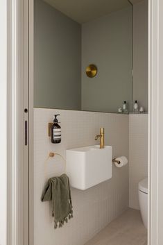 a bathroom with a sink, mirror and toilet paper roll hanging on the wall next to it