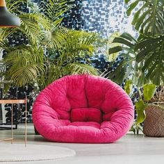 a pink chair sitting on top of a white floor next to potted plants and a lamp