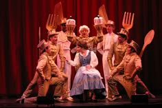 a group of people standing on top of a stage with utensils in their hands