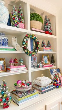 christmas decorations and wreaths are on the shelves in this white bookcase filled with books