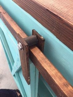 a close up of a wooden door handle on a blue painted cabinet with wood slats