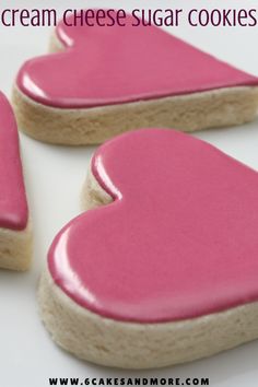 three heart shaped cookies with pink frosting on them and the words cream cheese sugar cookies