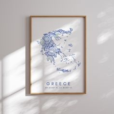 a blue and white poster hanging on the wall next to a wooden frame with an image of greece