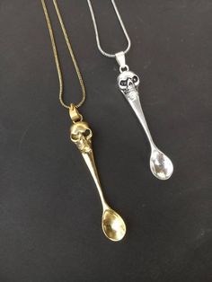 two silver spoons on a black surface with one gold spoon and the other silver spoon