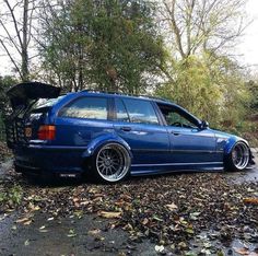 a blue car parked on the side of a road with its trunk open and it's hood up