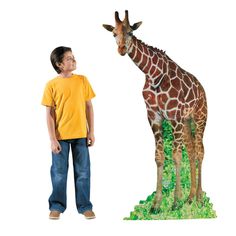 a young boy standing next to a fake giraffe