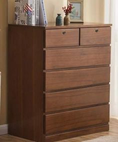 a wooden dresser sitting next to a window in a room with beige walls and wood floors