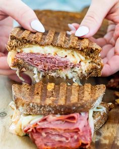 two hands holding a sandwich with meat and cheese