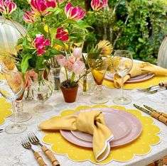 the table is set with yellow and pink flowers