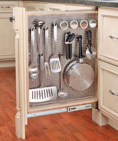 an open cabinet in the middle of a kitchen with utensils and pans