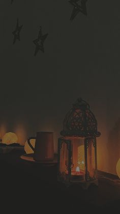 lit candles and teapots on a table in front of a wall with stars