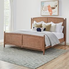 a wooden bed frame in a bedroom with hardwood floors and white walls, along with an area rug on the floor