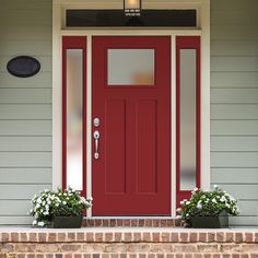 a red front door with two planters on the steps and a light above it