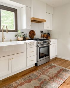 a kitchen with white cabinets and wood floors