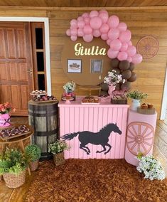 a horse themed birthday party with balloons and desserts on the table, in front of a pink carton