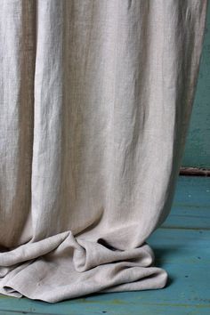 an unmade bed with a white blanket on top of it next to a blue wall