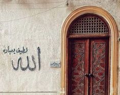 an arabic writing on the side of a building next to a wooden door and window