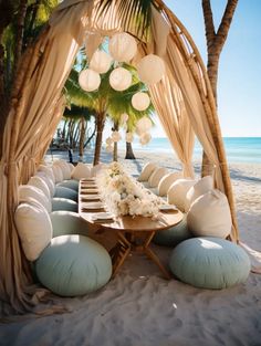 a wooden table sitting under a canopy on top of a sandy beach