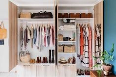 an organized closet with clothes, shoes and handbags on the shelves in front of it