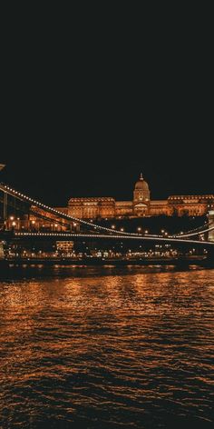 the bridge is lit up at night and it looks like it's going across the water