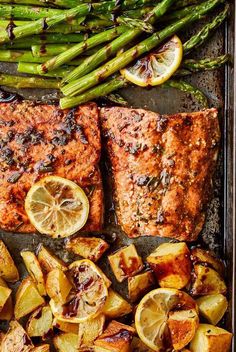 salmon, potatoes and asparagus on a baking sheet with lemon wedges for garnish