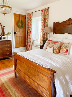 a bed sitting in a bedroom next to a dresser and window with curtains on it