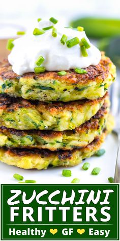 zucchini fritters with sour cream on top and green vegetables in the background