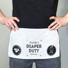 a man holding a white apron with the words daddy's diaper duty on it