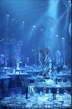 the tables are set for an event with blue lighting and balloons in the air above them