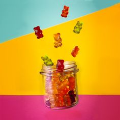 a jar filled with lots of gummy bears on top of a pink and yellow table