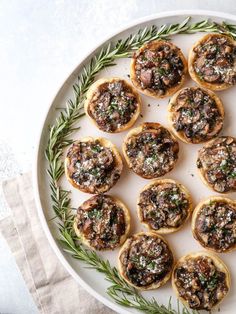 small appetizers are arranged on a plate with rosemary sprigs and seasoning