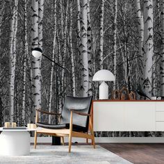 a living room with black and white trees on the wall, chair and table in front of it