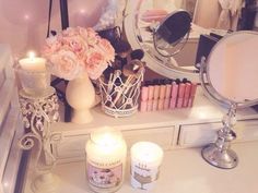 a vanity with candles, flowers and other items on it in front of a mirror