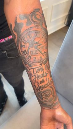 a person with a tattoo on their arm and wrist holding a clock in his hand