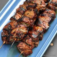 several skewers of meat on a blue plate