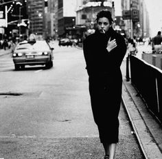 black and white photograph of woman walking down the street with her hand on her chest