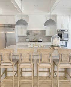 a kitchen with white cabinets and an island in the middle is surrounded by beige wicker chairs