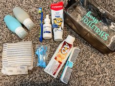 the contents of a personal care bag are laid out on the floor, including toothbrushes, mouthpaste, and other items