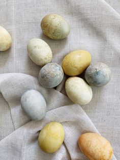 several different colored eggs sitting on top of a white cloth next to each other, with one yellow and one blue egg in the middle