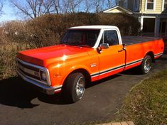 an orange pickup truck parked in front of a house