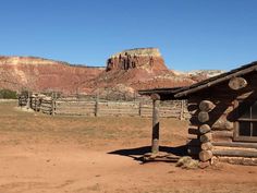 an old log cabin in front of a mountain