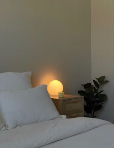 a bed with white sheets and pillows next to a lamp on the side of it